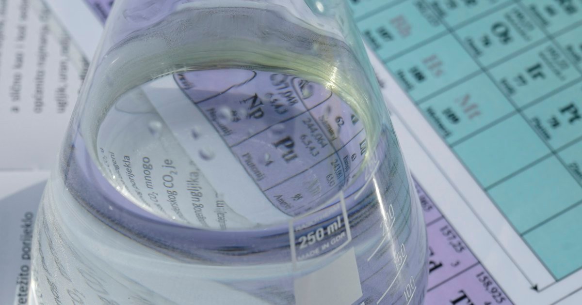 Laboratory flask of clear water resting on a printed chart