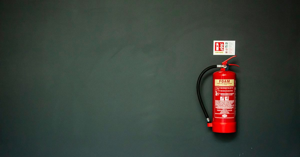 Red fire extinguisher mounted on a dark grey wall
