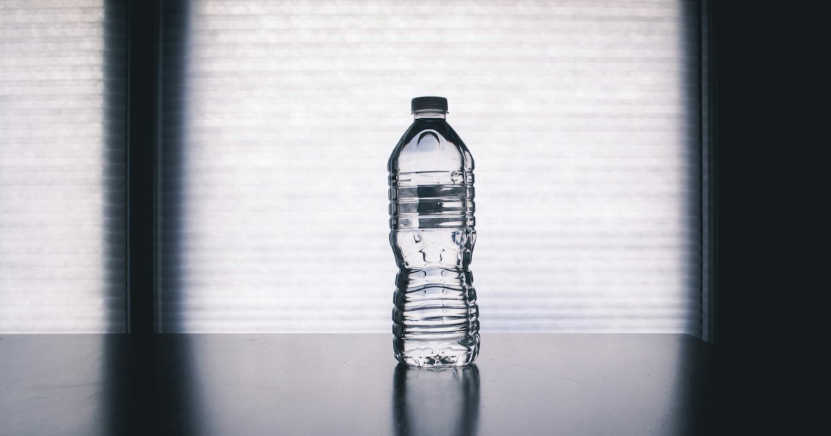 A clear unlabelled plastic water bottle on a table by a window